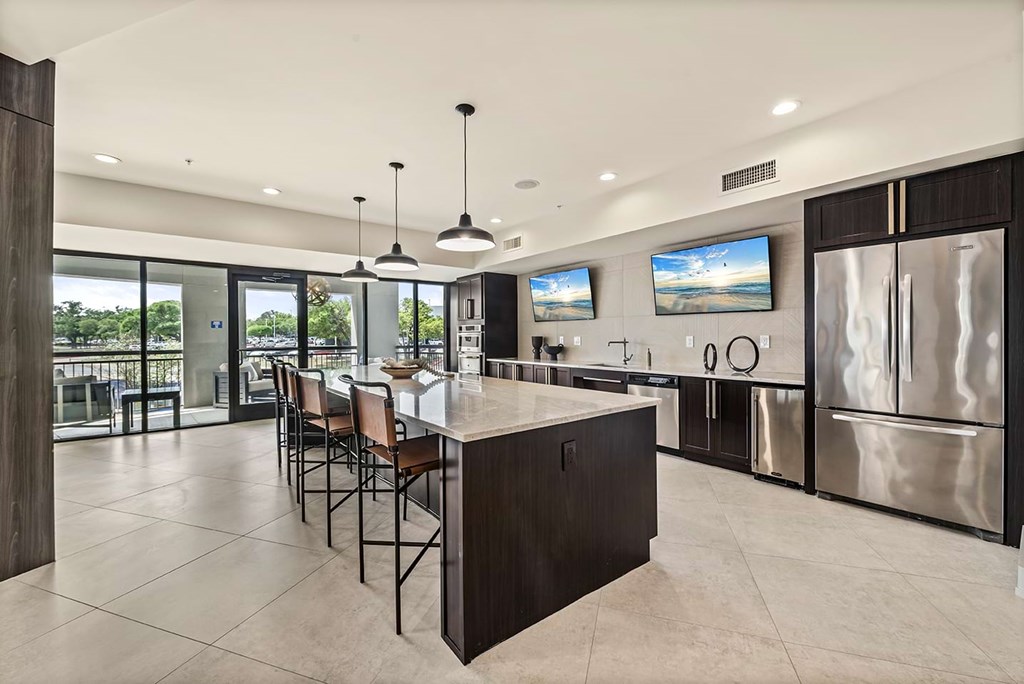 Modern kitchen here at The Reserve at Arboretum Apartment Homes with dark wood cabinets, sleek island, and stainless steel appliances. Large windows offer natural light, creating an airy atmosphere.