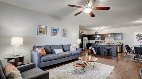 A living room with a grey couch, a coffee table, and a ceiling fan.