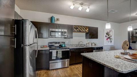 A modern kitchen with a granite countertop and stainless steel appliances.