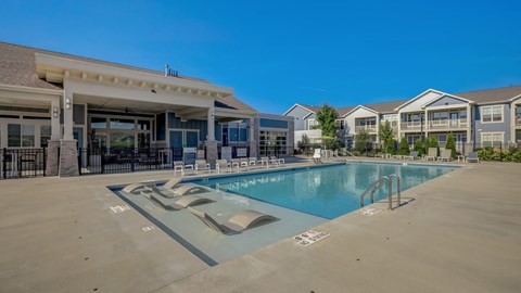A large swimming pool with a slide and a building in the background.