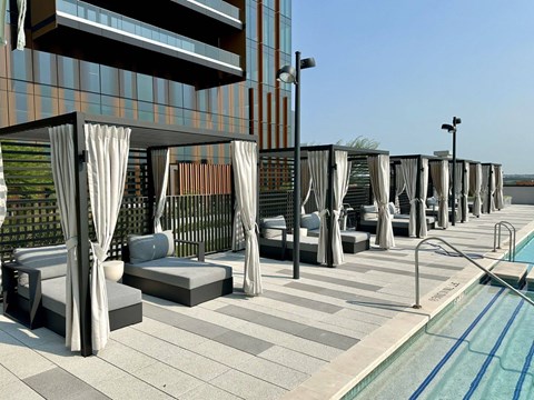A poolside area with lounge chairs and curtains.