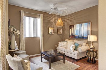 A living room with a ceiling fan and window overlooking the property Pala Mesa Living Room - Photo Gallery 5