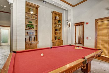 A lounge for residents with a pool table, chairs, and bookshelves Property Image