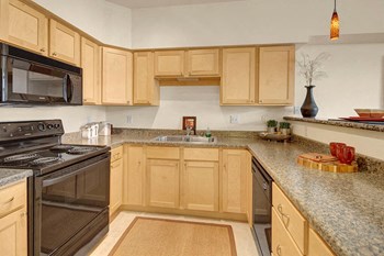 A kitchen with sleek black appliances and granite countertops Park Plaza II Kitchen - Photo Gallery 3