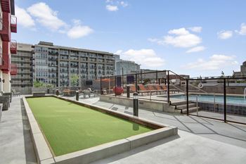 a green astroturf soccer field on a rooftop patio with a pool in the background