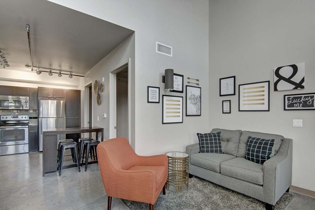 a living room with a couch chair and a dining room table in the background