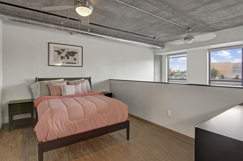 a bedroom with a bed and two windows