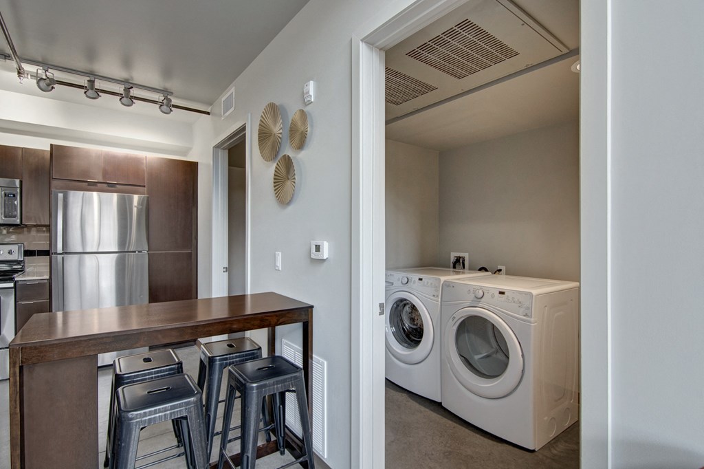 a kitchen with a washer and dryer and a table with stools