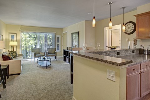 a kitchen with an island and a living room in the background
