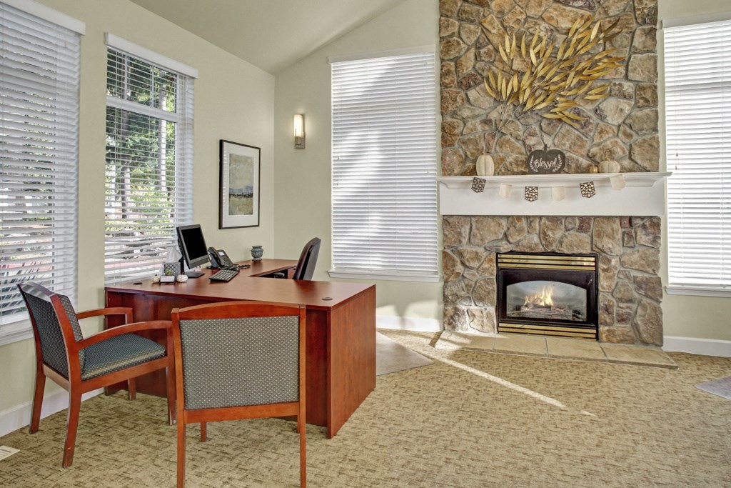 a room with a fireplace and a desk and chairs