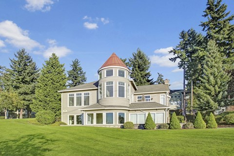 a large house with a tower on top of a grassy hill