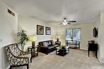 A living room with a ceiling fan and sliding glass doors Reserve at Arrowhead Living Room - Photo Gallery 5