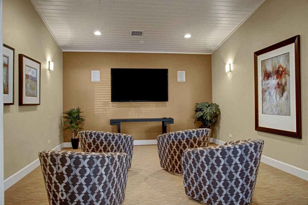 a room with a couch and chairs and a flat screen tv on the wall