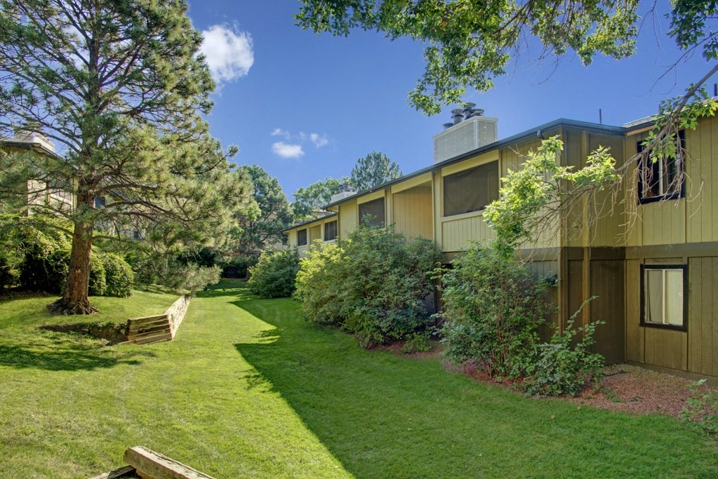 a building with a green lawn and trees in front of it
