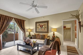 A living room with a sliding glass door and ceiling fan Retreat at Speedway Resident Lounge - Photo Gallery 6