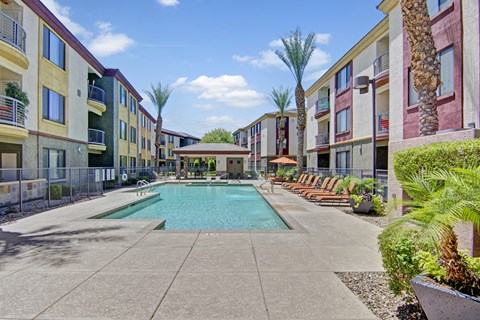 A pool surrounded by palm trees and apartment buildings.