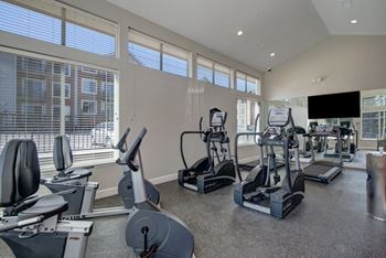 a gym with cardio machines and a flat screen tv