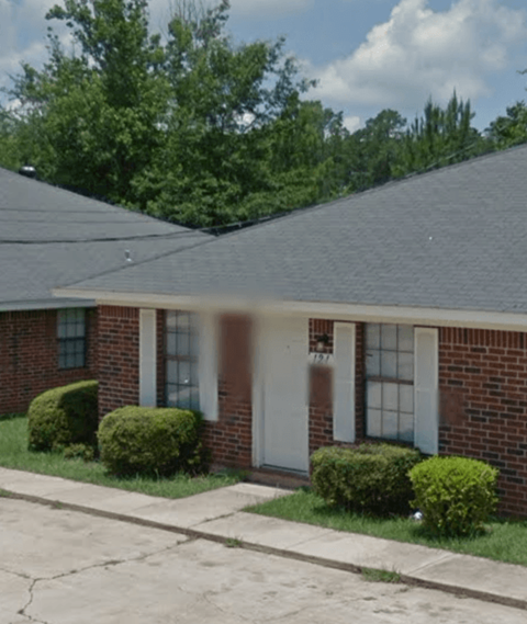 a brick house with a gray roof and a sidewalk