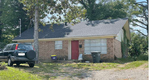 a small brick house with a car parked outside
