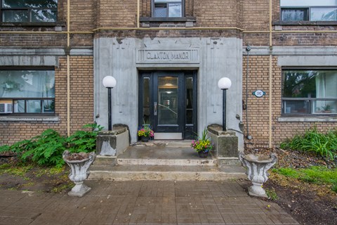 The front of a brick building with a black door and windows.