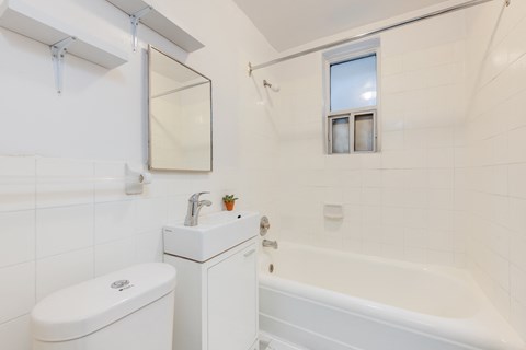 A white bathroom with a toilet, sink, and bathtub.