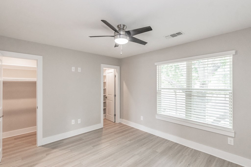 Bedroom with large window and ceiling fan in Riata Park Apartment