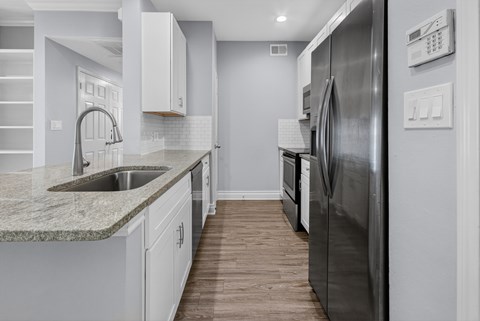 A modern kitchen with a stainless steel refrigerator and a marble countertop.