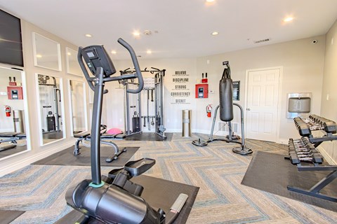 A gym with a variety of equipment including treadmills, weights, and exercise machines.