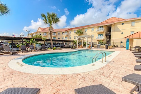 A large outdoor swimming pool surrounded by lounge chairs and umbrellas.