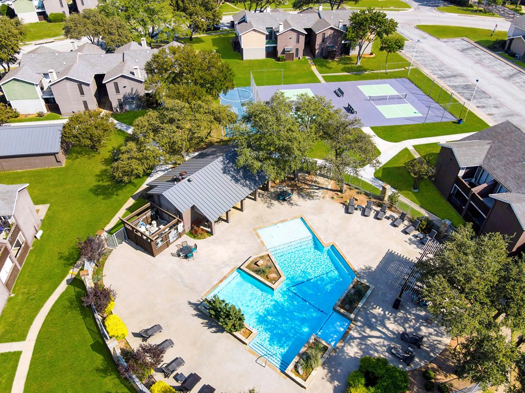 Aerial view of resort-style pool, courts, and green spaces at Station 121