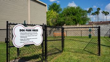 a dog park rules sign on a fence in front of a house