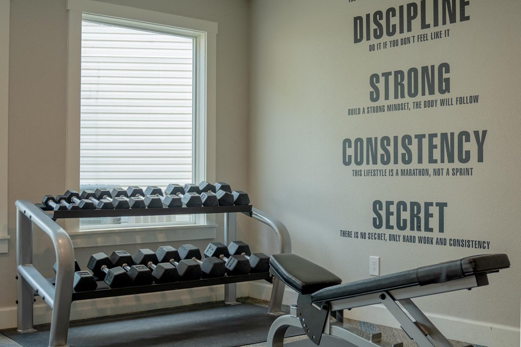 a gym with weights and a wall with a quote on it