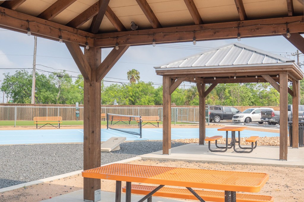 a pavilion with picnic tables at a park with a basketball court