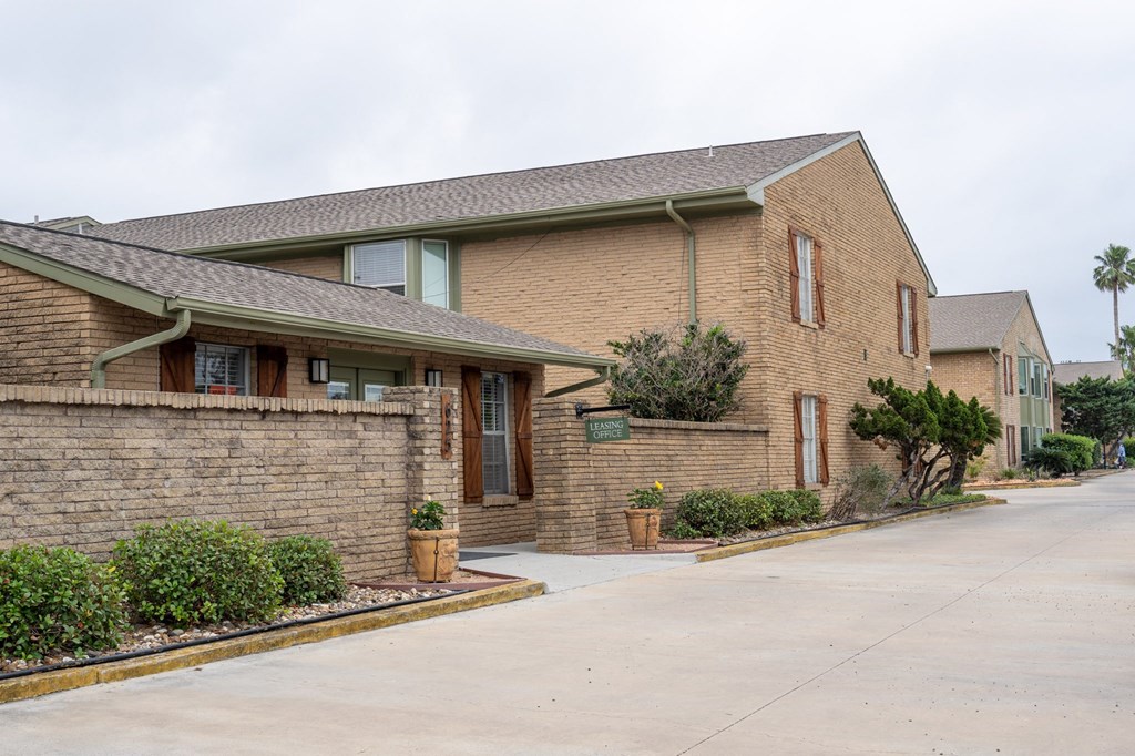 the front of a brick building with a driveway and a street