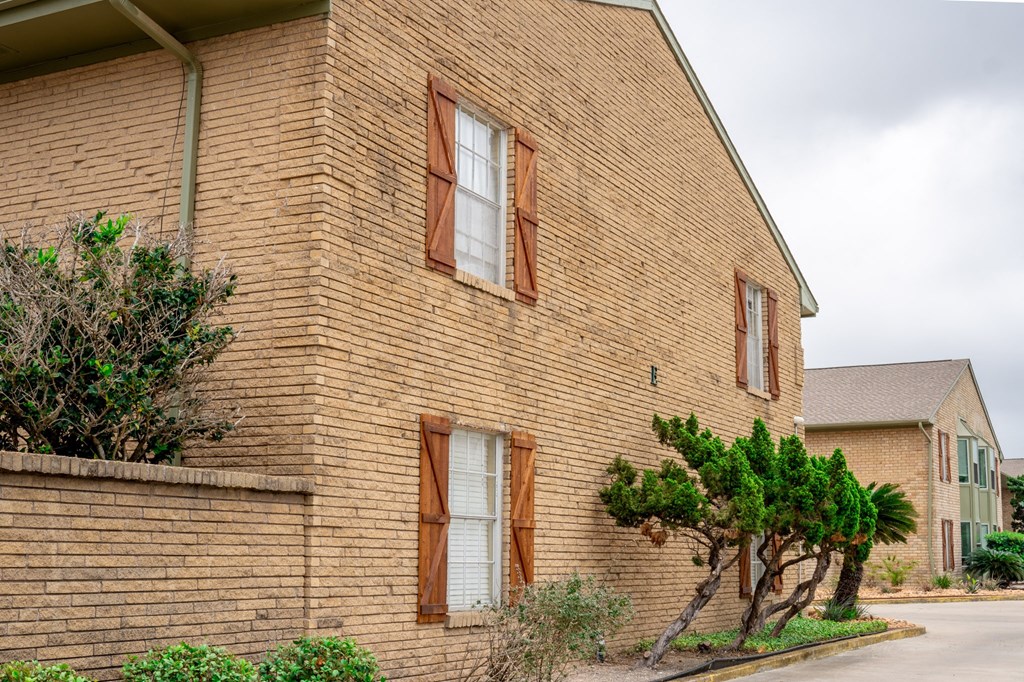 a brick building with two windows and a street in front of it