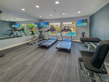 A gym with treadmills, exercise bikes, and a television.