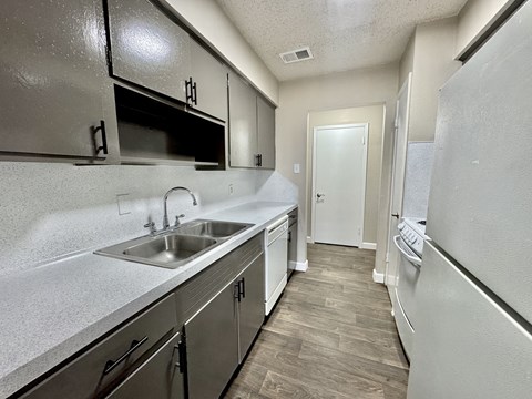 A kitchen with a white fridge, stainless steel sink and cabinets.