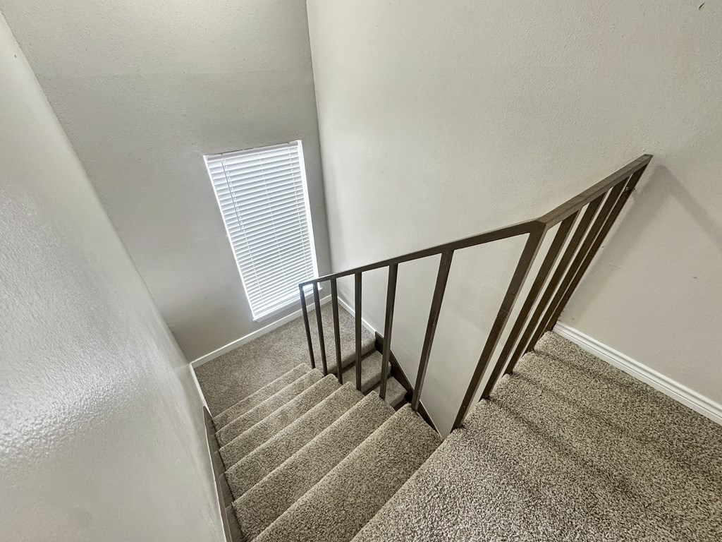 A staircase with a metal railing and carpeted steps.