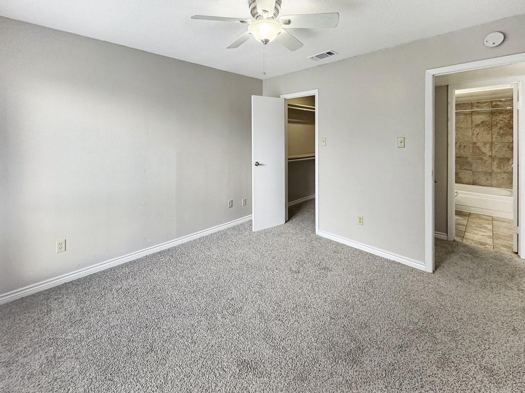 A room with a carpeted floor and a ceiling fan.