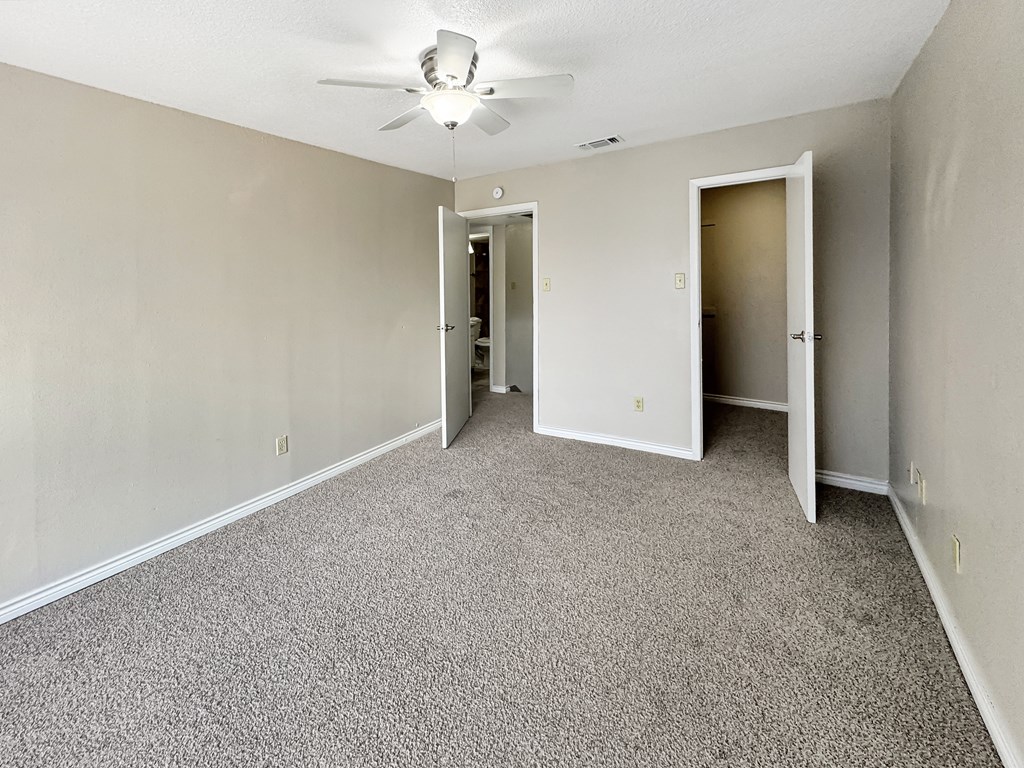 A room with a ceiling fan and carpeted floor.