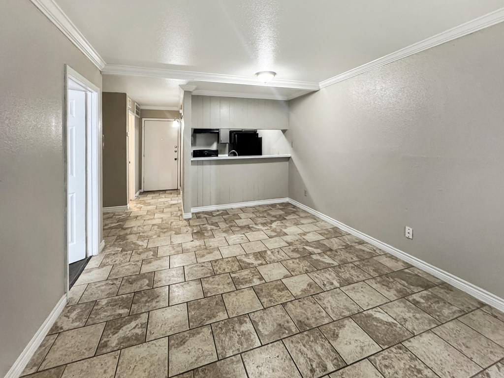 A room with a tiled floor and a small kitchenette.