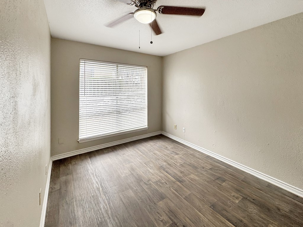 A room with a ceiling fan and a window with blinds.
