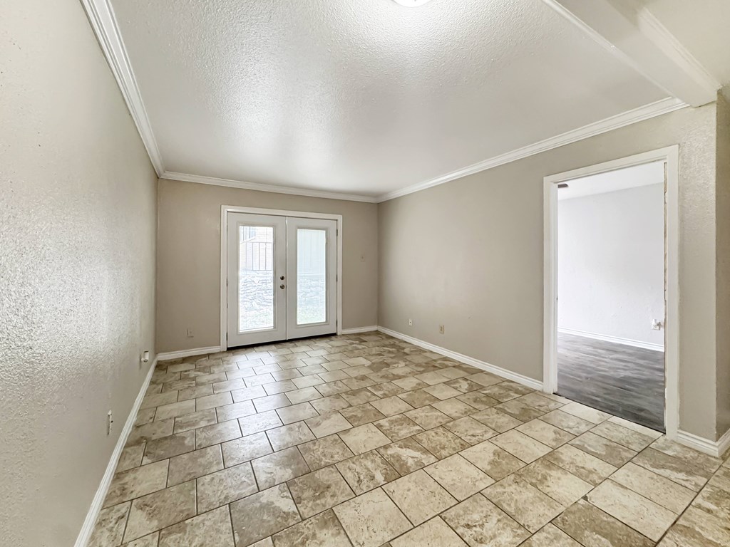 A room with tiled flooring and a sliding glass door leading to a balcony.