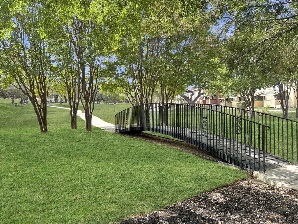 A black metal fence borders a grassy area with trees.