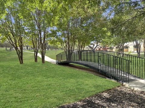 A black metal fence borders a grassy area with trees.