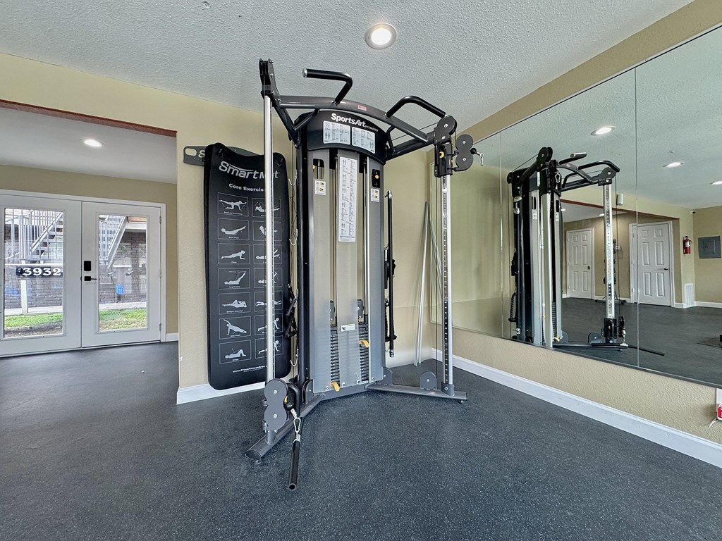 Fitness room with cable machine and mirrors at Christy Estates Apartments