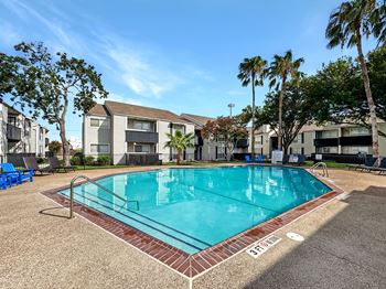 A swimming pool surrounded by palm trees and apartment buildings.