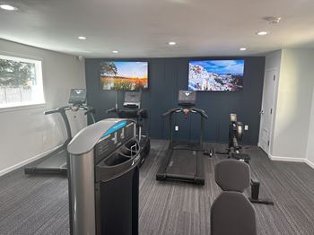 a gym with treadmills and televisions in a building