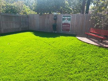 a backyard with a green lawn and a red bench