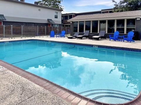 A swimming pool with blue chairs around it.